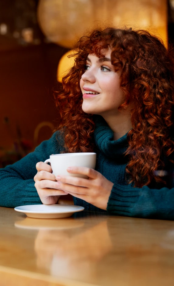 A person sat at a table with a cup and saucer