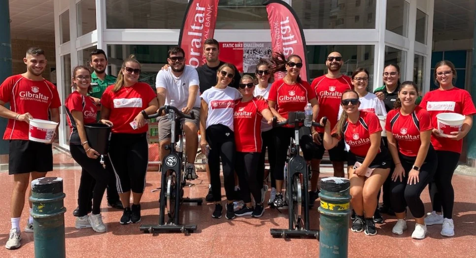 People at a charity event holding collection buckets and wearing Velantis Trust International Bank t-shirts